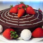 chocolate cake with white spider web design and strawberries on top