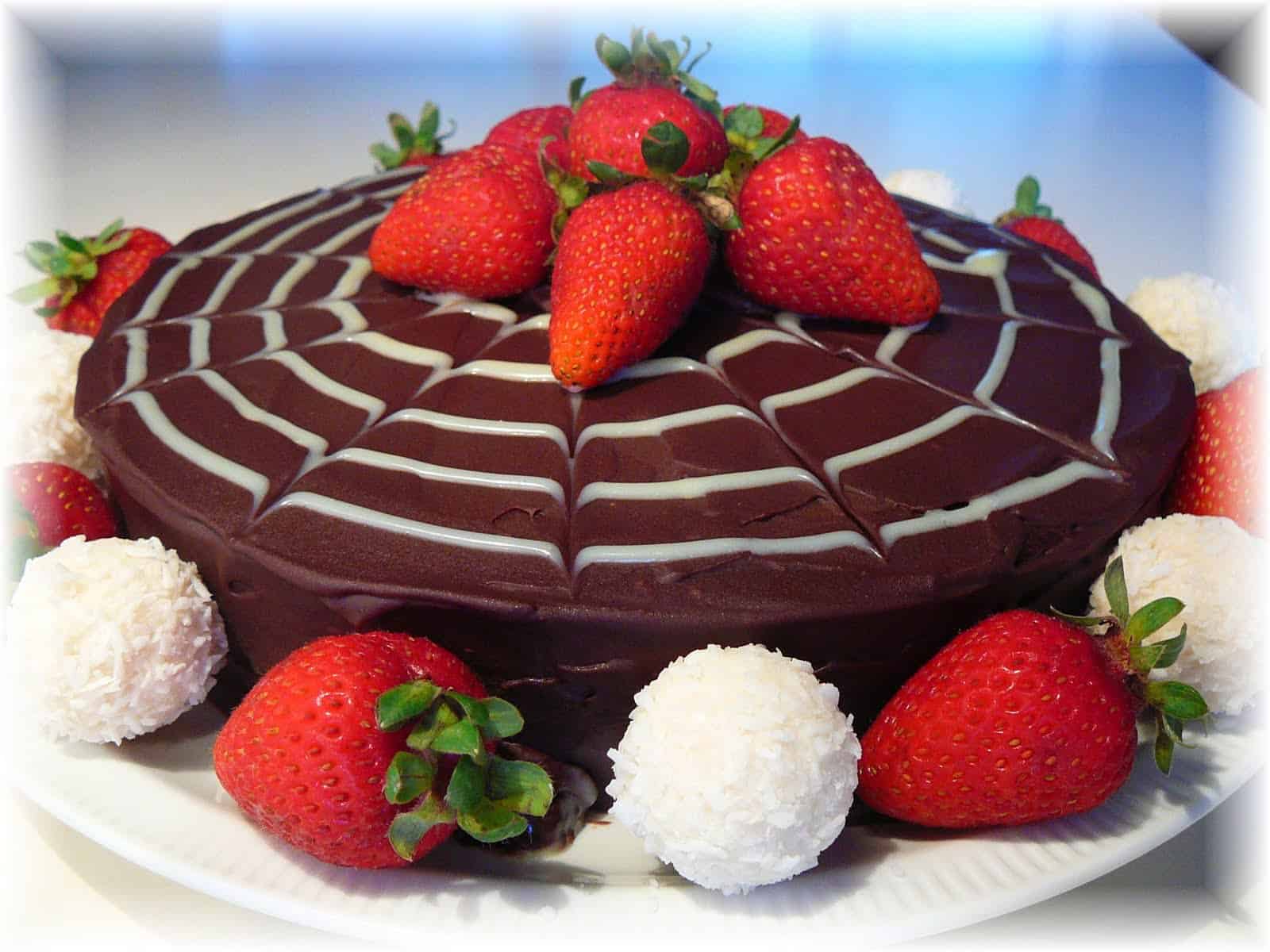 chocolate cake with white spider web design and strawberries on top