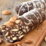 two chocolate salami on wooden board with three slices cut