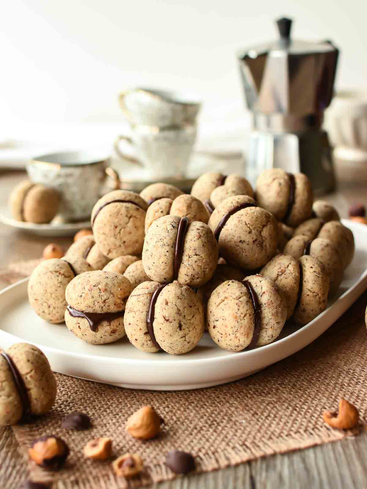 Pile of chocolate sandwiched hazelnut cookies on a white plate.