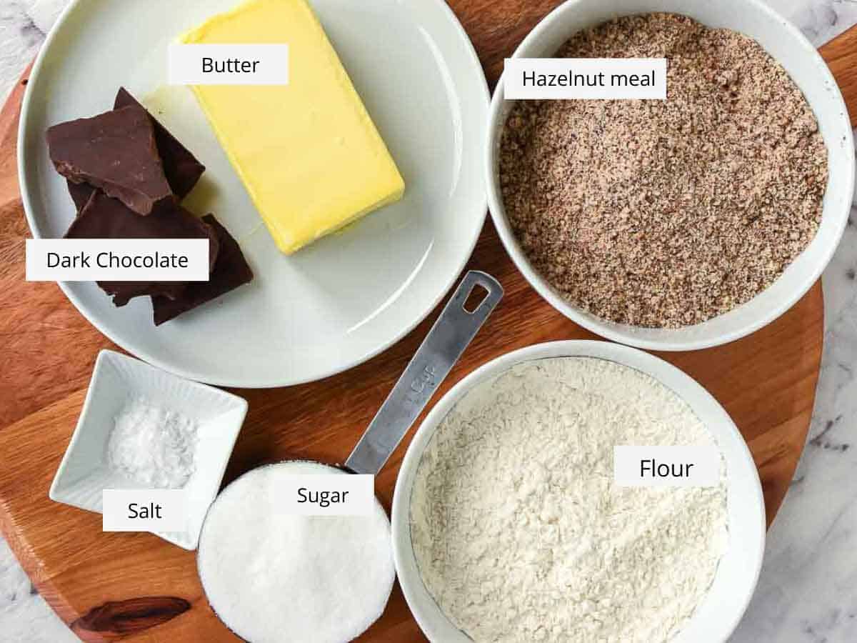 ingredients for hazelnut cookies viewed from above - butter, ground hazelnuts, flour, sugar, salt and chocolate.