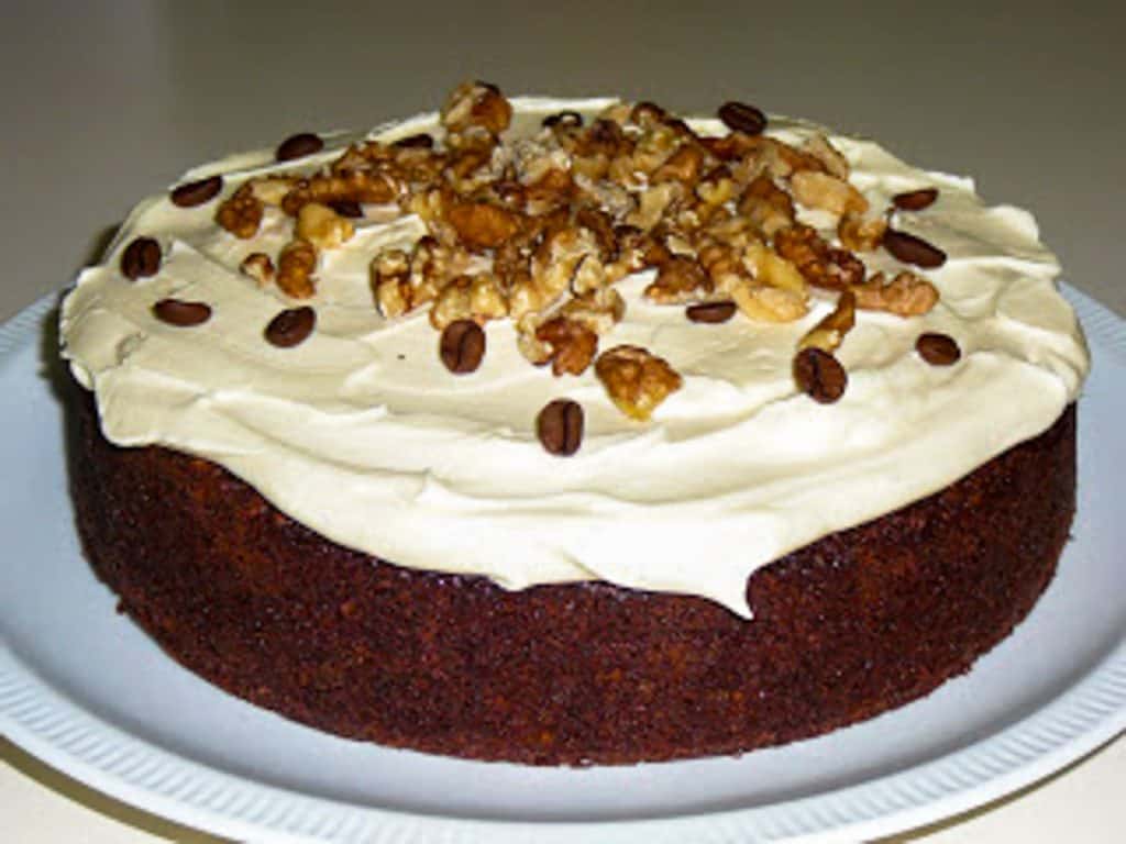 brown cake with white frosting and walnuts sprinkled on top.