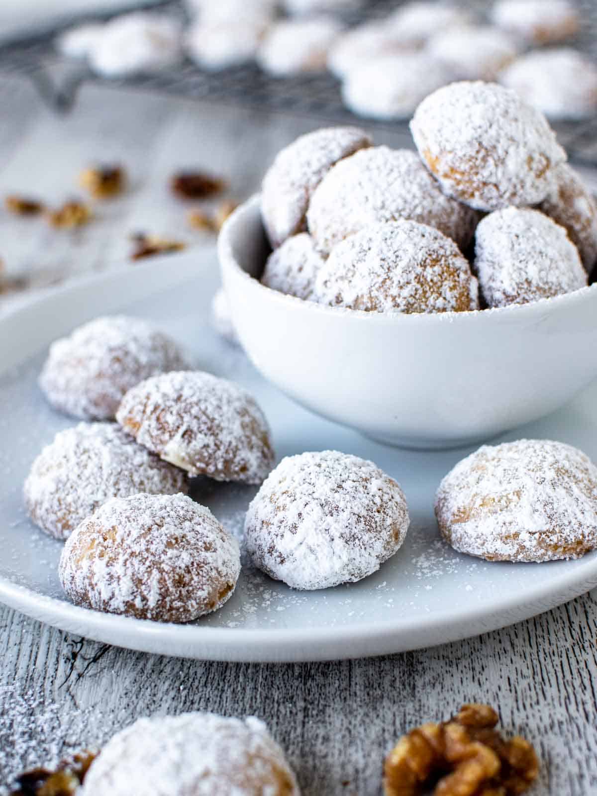 White sugar coated Norwegian cookies on blue plate plus more in white bowl.