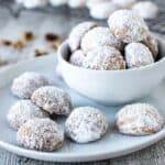 White sugar coated Norwegian cookies on blue plate plus more in white bowl.