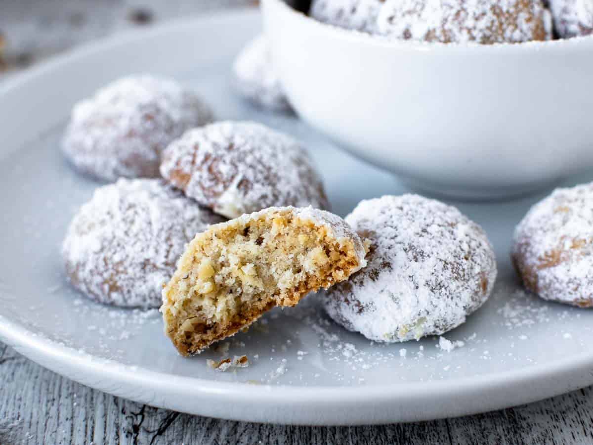 Close up of halved cookie coated in white powdered sugar with extra cookies around.