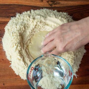 Water being added to a well of semolina flour and hand mixing.