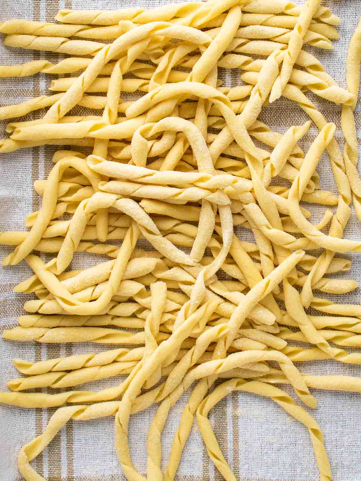 Busiate pasta on a kitchen towel viewed from above.