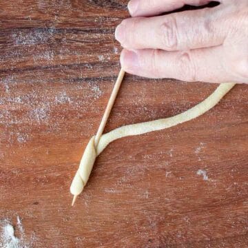 A bamboo skewer with a strand of dough wound a couple of times around it.