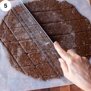 Rolled out brown cookie dough being cut into diamond shapes.