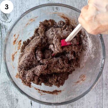 Brown dough being mixed with a red spatula.