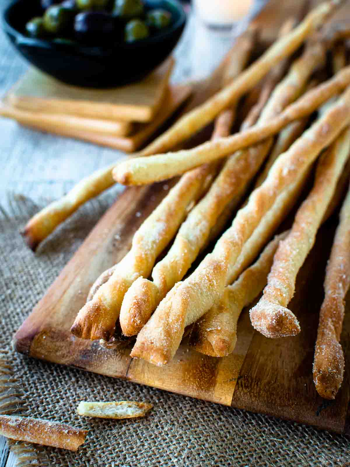 Bunch of grissini breadsticks on a wooden board.