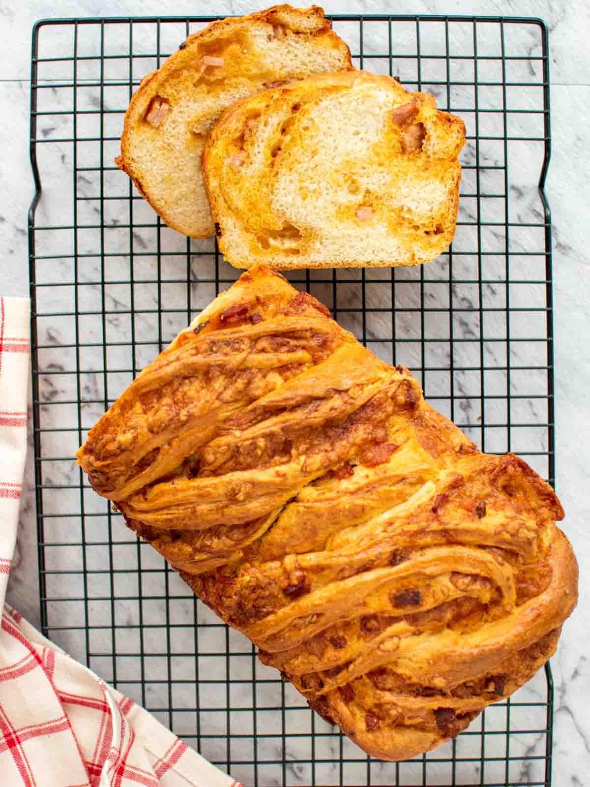 Bacon cheese bread on black wire rack with two slices cut viewed from above