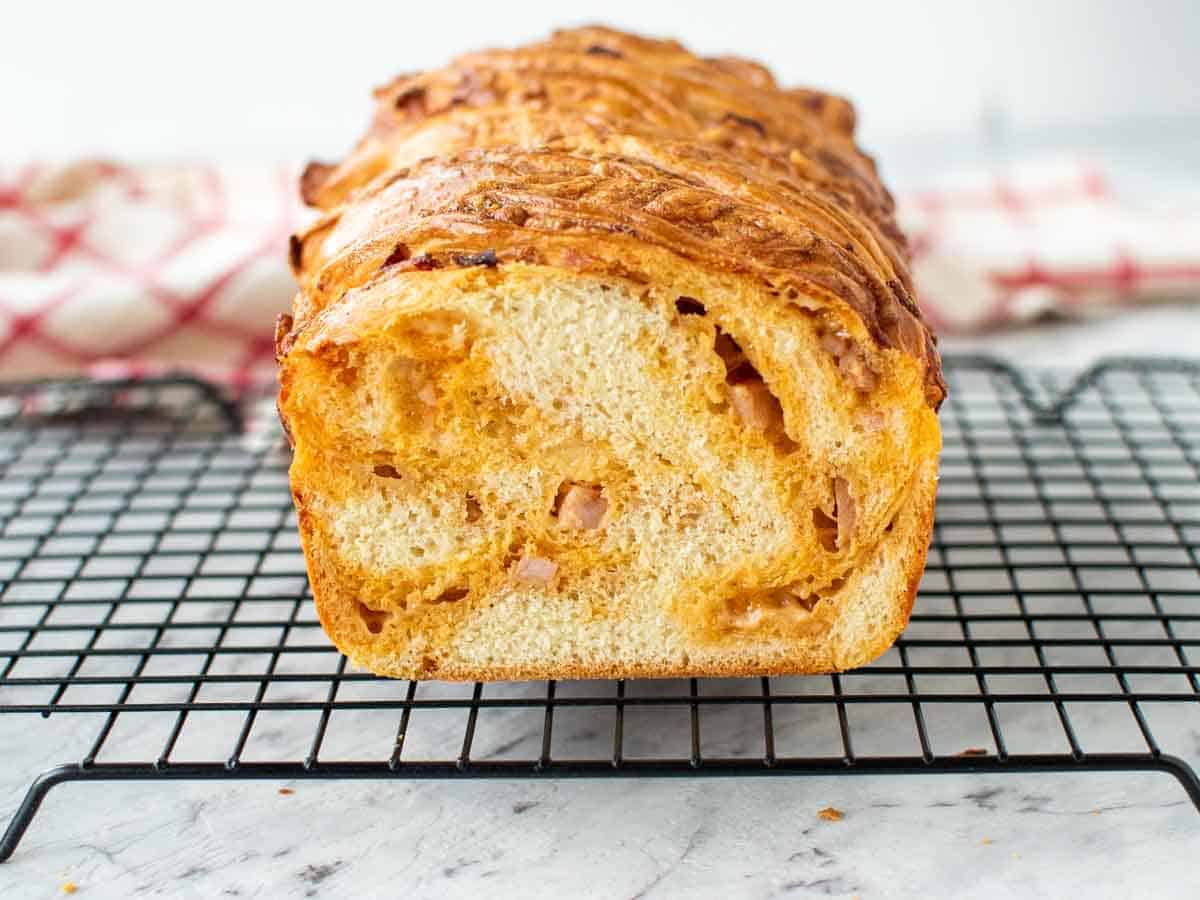 Cross section of cheese filled Bread loaf on black wire rack.