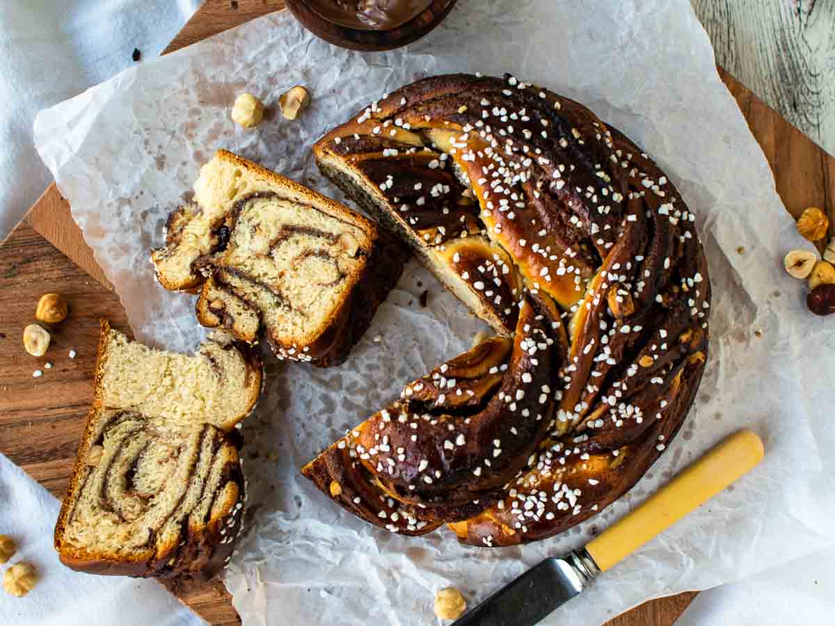 Overhead view of dark brown, round sweet bread with two slices cut, showing chocolate swirls inside,