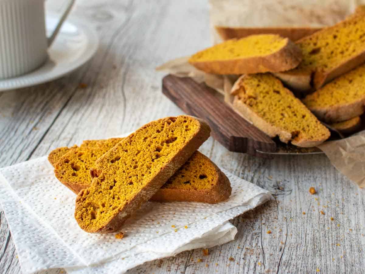 Close up of two stacked pumpkin spice biscotti with more in the background.