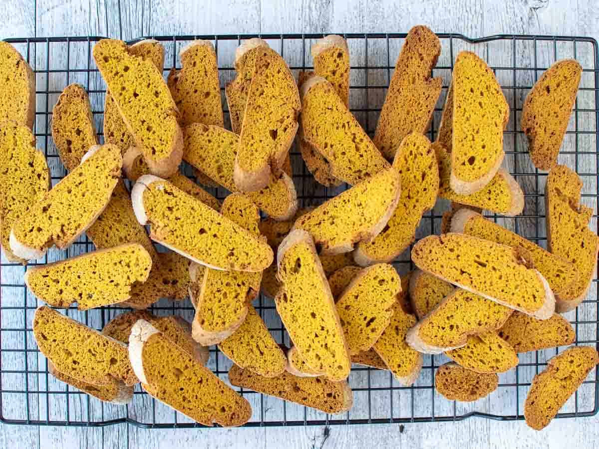 Orange brown biscotti piled up on a wire cooling rack.