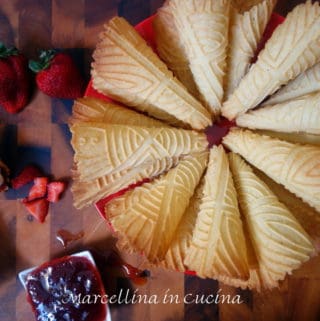 Krumkake cones arrange in a circle with jam and cream on the side