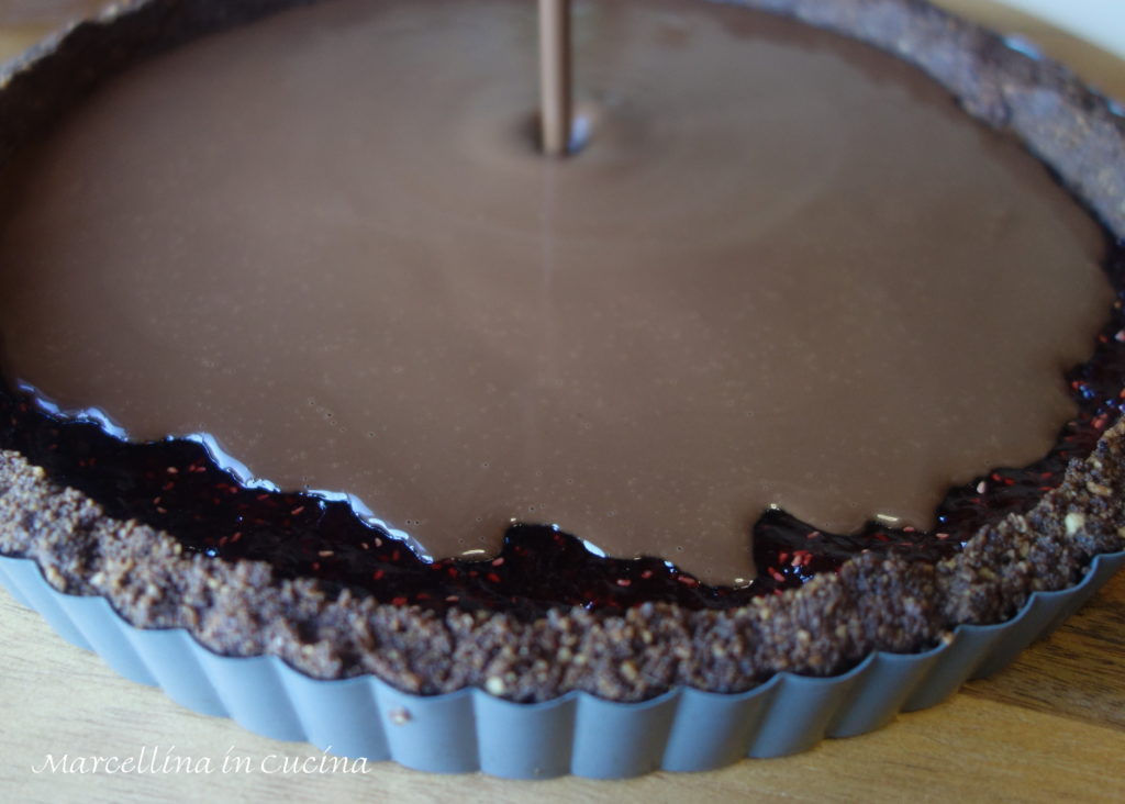 Pouring chocolate filling over raspberry jam
