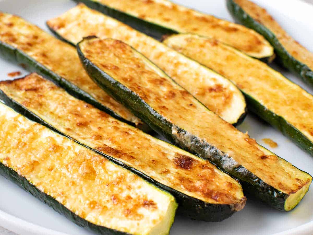 close up of a pile of cheese topped roasted zucchini halves.