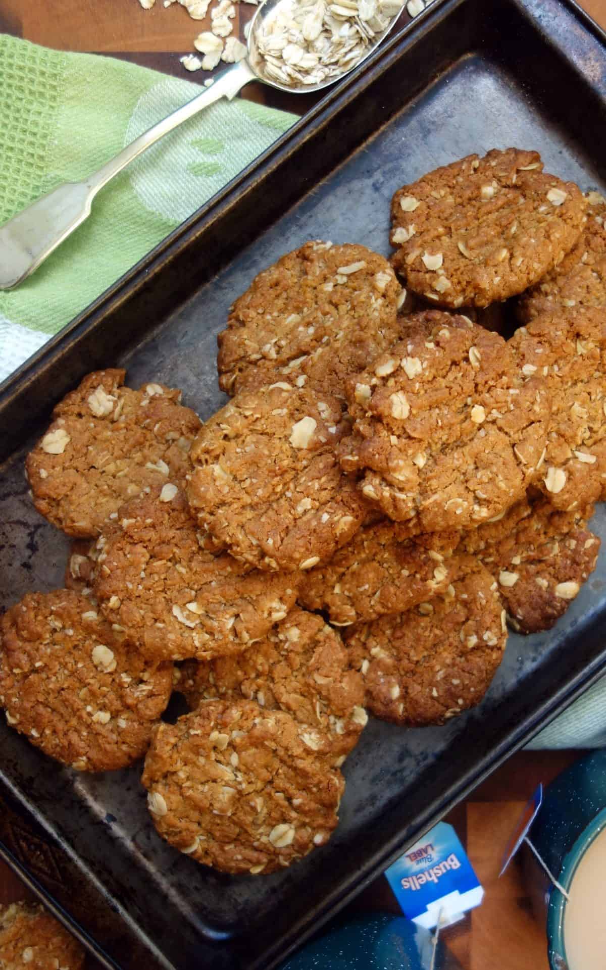 Overhead view of Anzac Biscuits in dark coloured baking tray