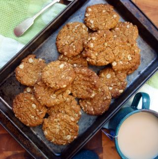 Overhead view of Anzac Biscuits in dark coloured baking tray