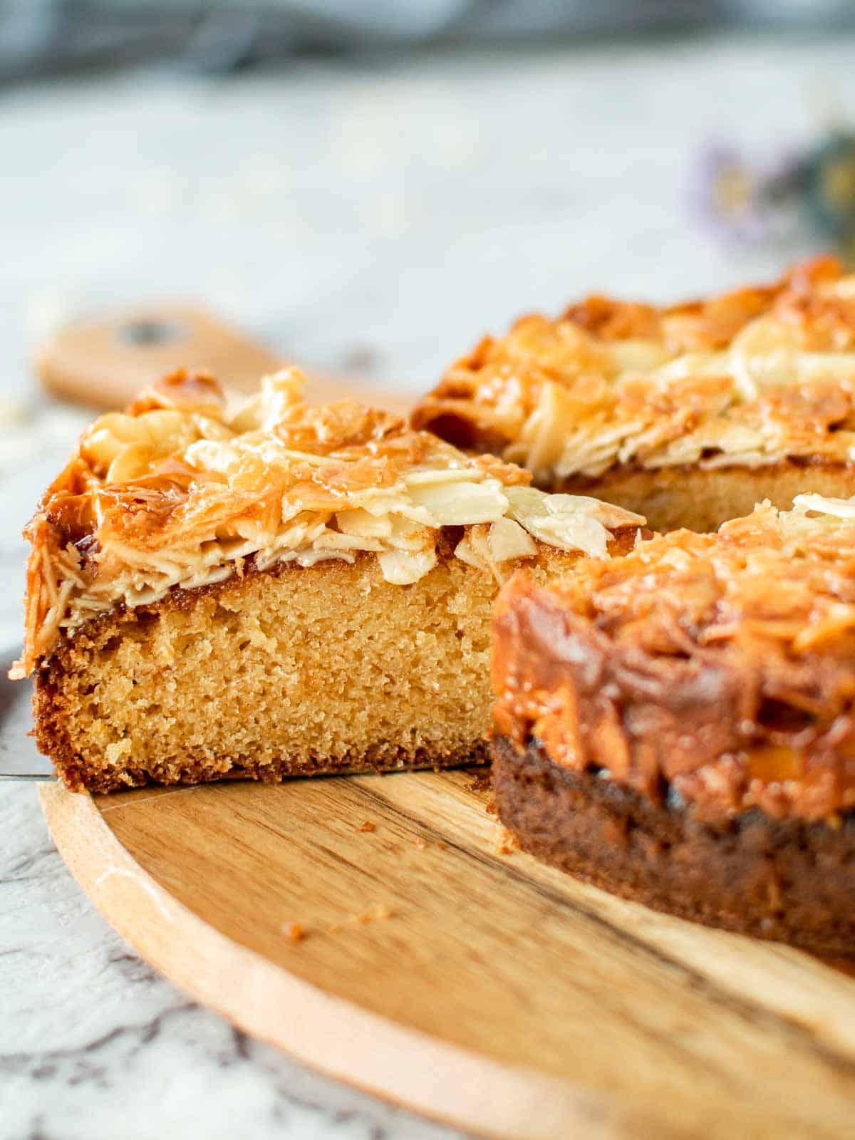 slice of cake with almond topping cut from whole cake viewed side on.