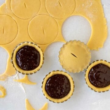 Tartlet filled with chocolate, pastry rolled out and circles cut.
