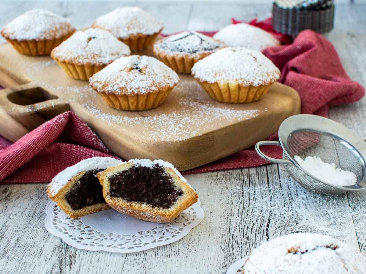 Small chocolate pies on a wooden board with one cut in half at the front.