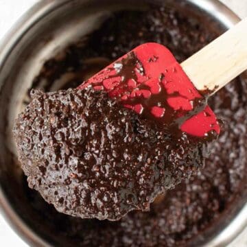 Brown shiny, coarse mixture on a red spatula.