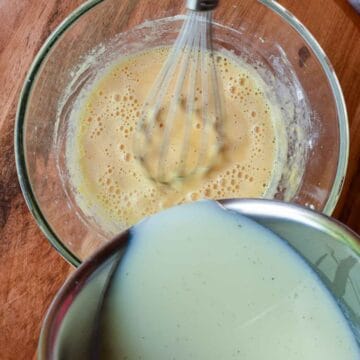 Milk being poured into a bowl of yellow liquid.