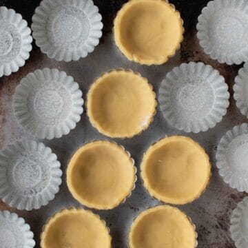 Overhead view of mini tartlet pans some lined with pastry.