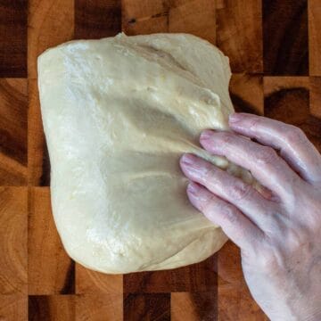 Dough shown being folded by hand.