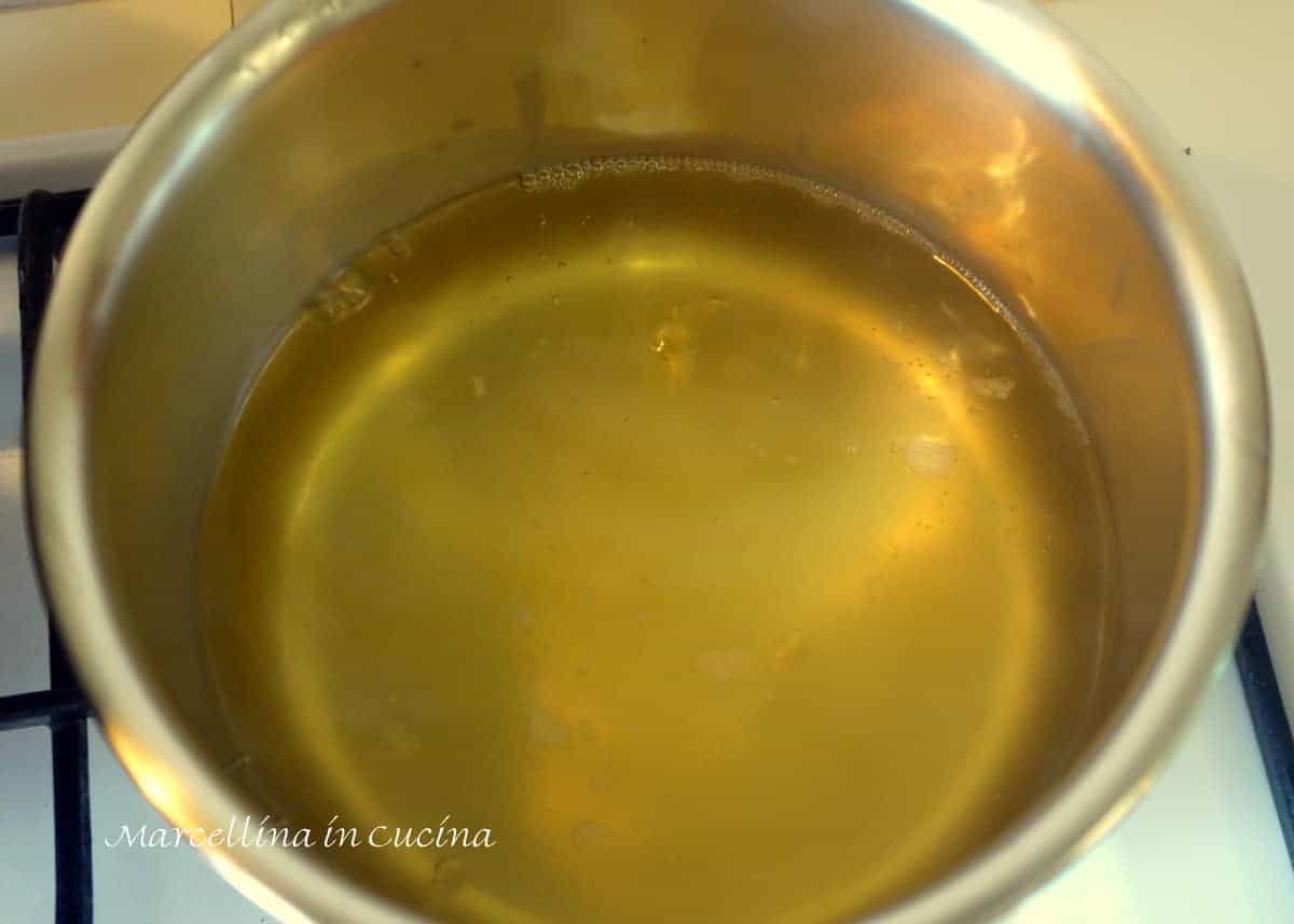 Chicken broth heating in saucepan.