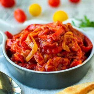 Stewed bell pepper and tomatoes in blue bowl.