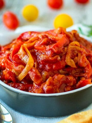 Stewed bell pepper and tomatoes in blue bowl.