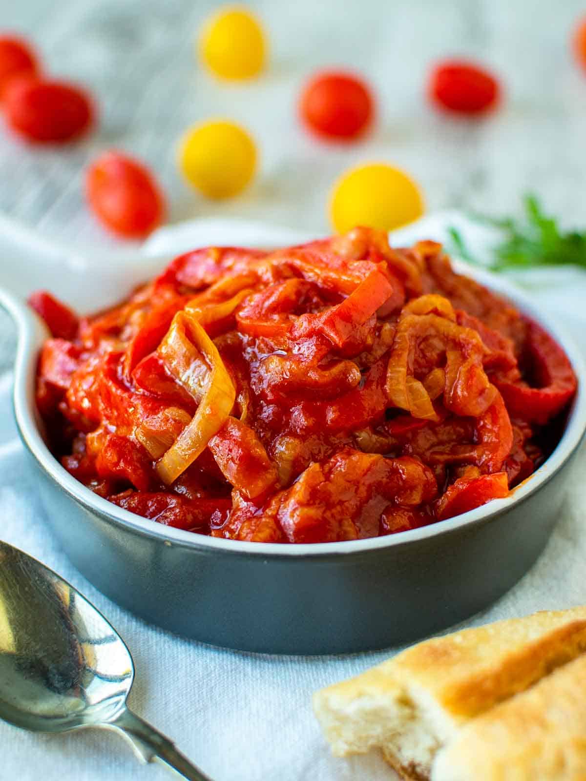 Stewed peperonata using bell pepper and tomatoes in blue bowl.