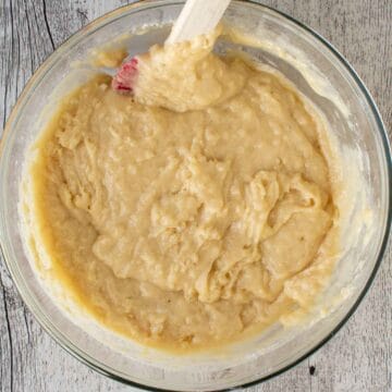 Pale yellow muffin batter in a glass bowl.