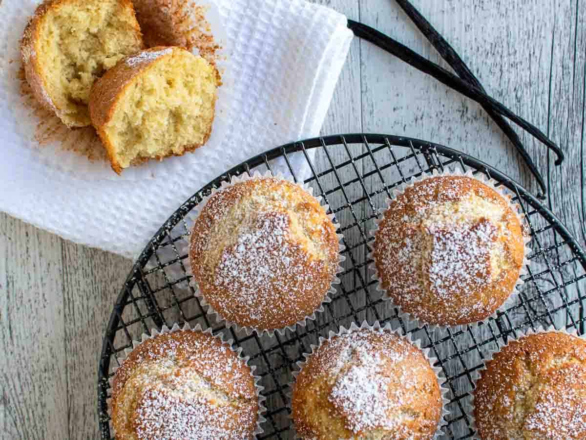 Overhead view of plain muffins sprinkled with powdered sugar and one broken open.