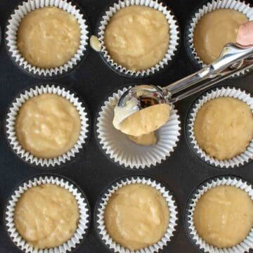 Batter being scooped into muffins liners.