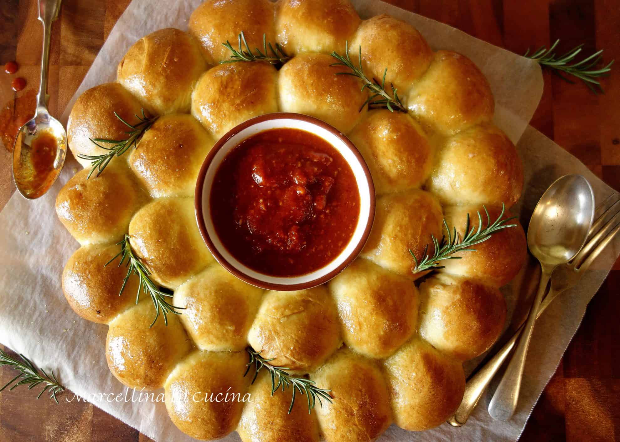 wreath made of bread with tomato dipping sauce in the middle.