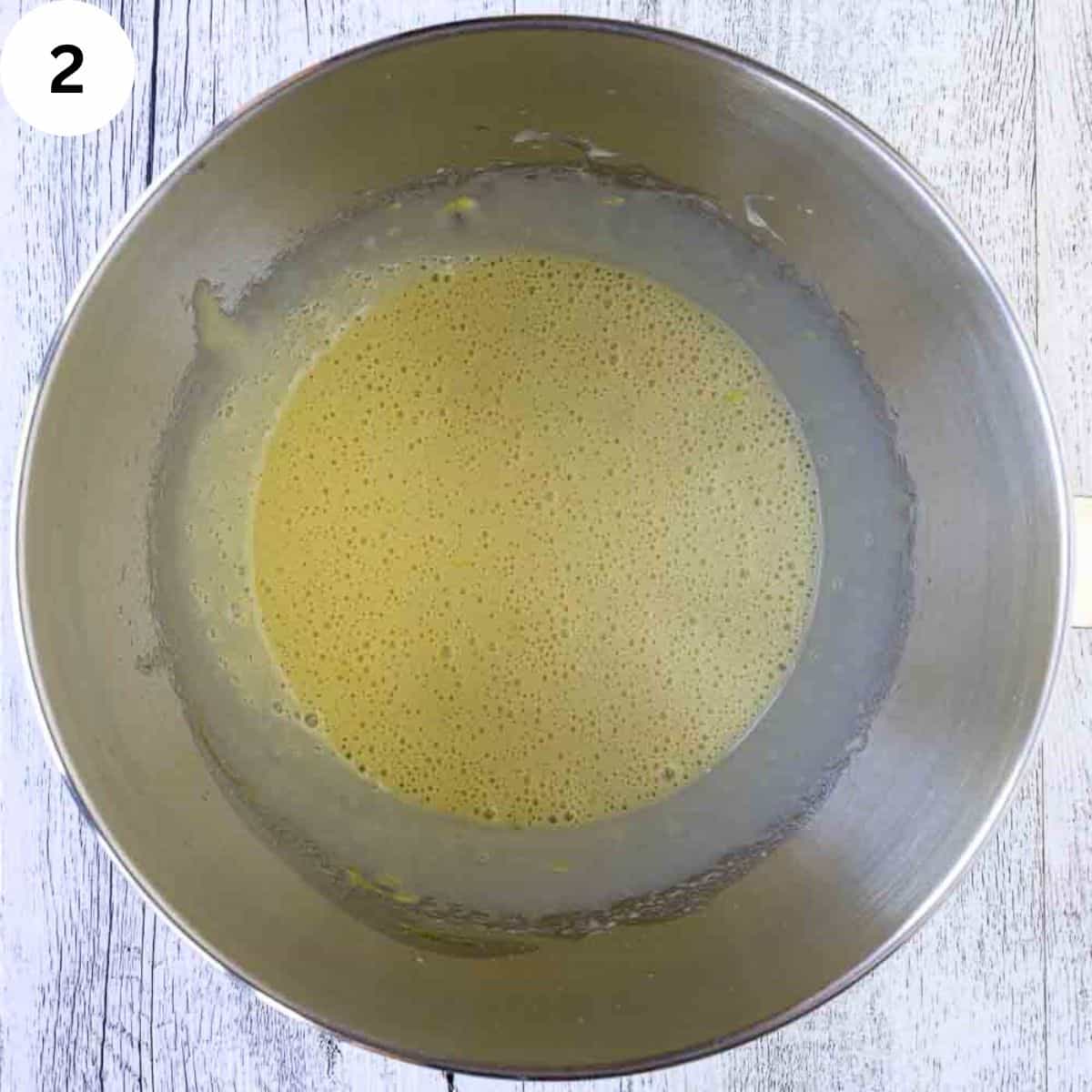 Yellow frothy batter in stainless steel bowl.