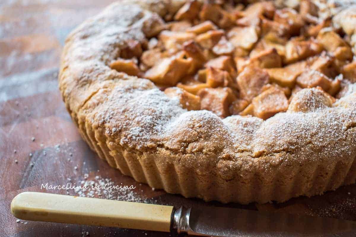 close up of tart filled with apples and a bone handle knife in front.
