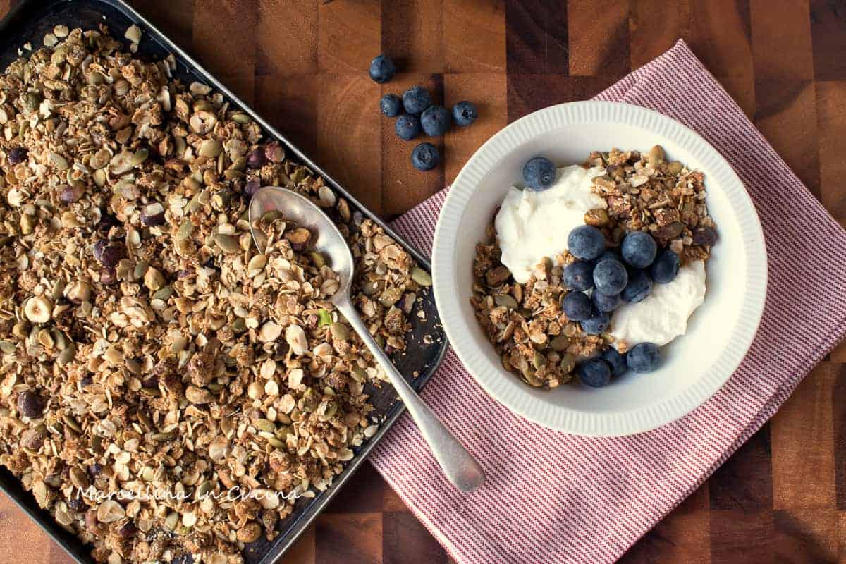 Tray of gluten-free granola with red and white cloth and bowl of granola, yogurt and blueberries.