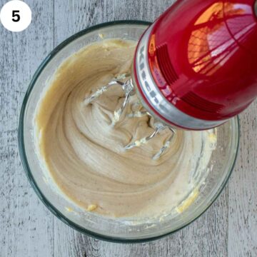 Creamy frosting being beating with an electric mixer.