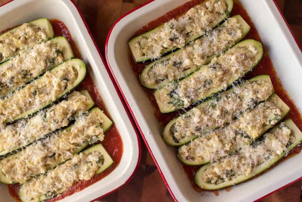 Two baking trays of unbaked Stuffed Zucchini with Ricotta in tomato sauce