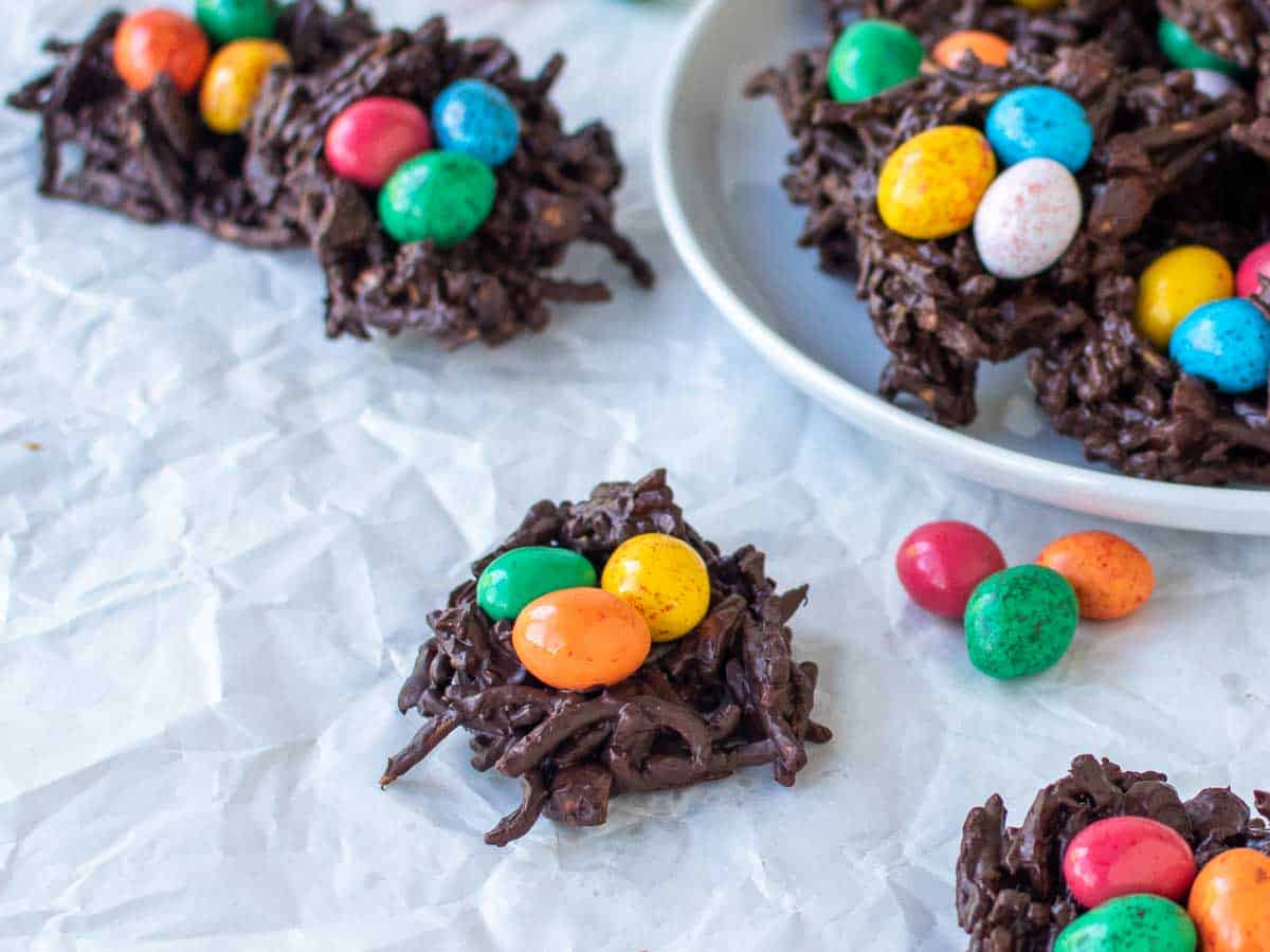 Close up of chocolate and noodle nests with candy eggs inside.