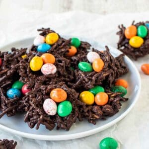 Chocolate nests with colored candy eggs on a white plate.