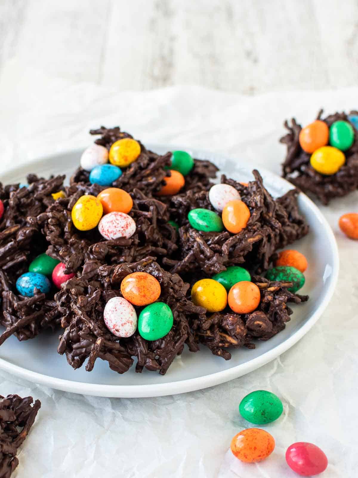 Chocolate Bird's Nest Cookies with colored candy eggs on a white plate.