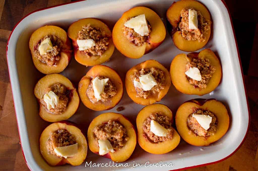 Peaches stuffed with amaretti and topped with knob of butter ready for baking
