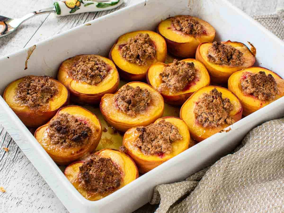 45 degree view into a white baking dish of filled baked peaches.